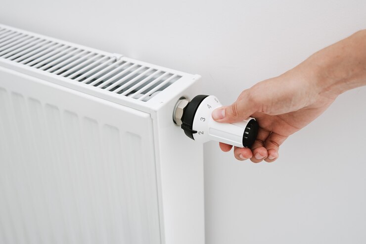 Mano della donna che regola la temperatura sul radiatore di calore