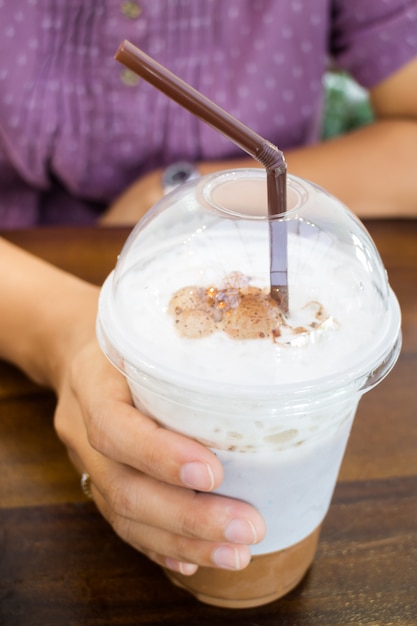 Mano della donna che tiene caffè ghiacciato