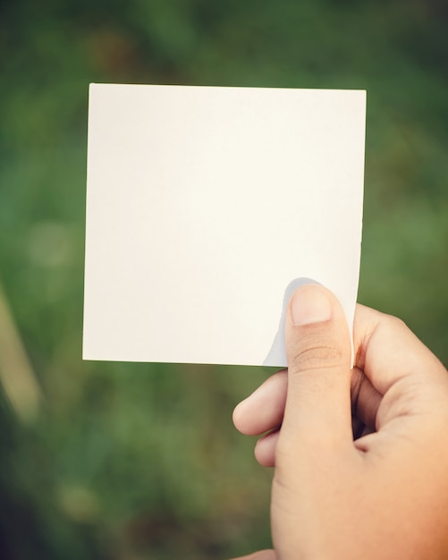 Mano della donna che tiene carta in bianco sulla natura