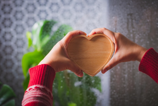 Mano della donna che tiene cuore di legno