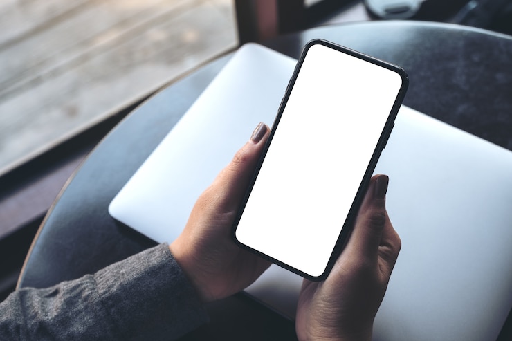 Foto mano della donna che tiene il cellulare nero con schermo desktop bianco vuoto