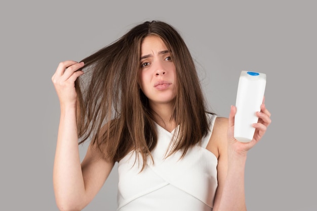Mano della donna che tiene lo shampoo bootle con grave problema di caduta dei capelli per lo shampoo sanitario