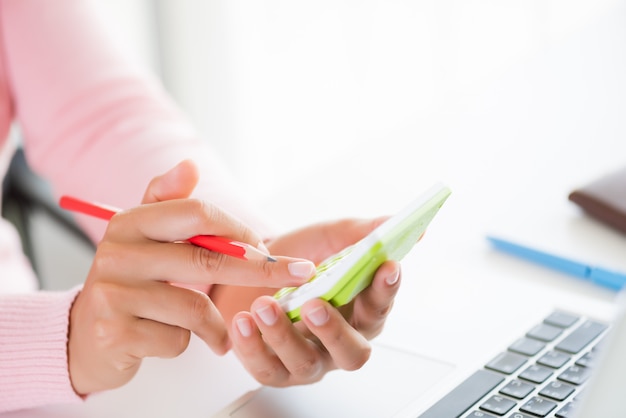 Mano della donna che tiene matita rossa e lavorando con calcolatrice, documento aziendale e laptop co