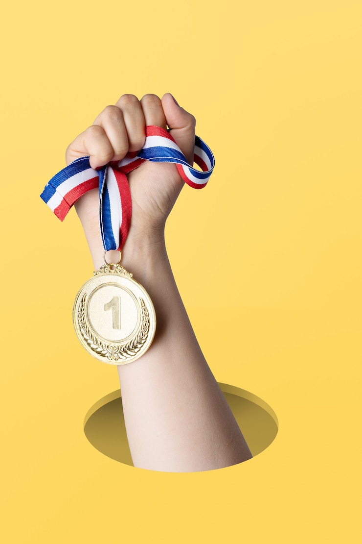 Foto mano della donna che tiene medaglia d'oro su sfondo giallo.concetto premio e vittoria.copia spazio