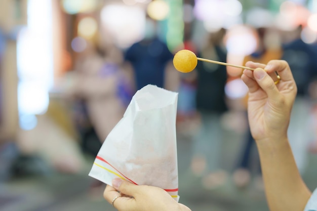 Mano della donna che tiene palla di patate dolci al mercato notturno famoso cibo di strada taiwanese di cibo esotico di Taiwan nel mercato locale