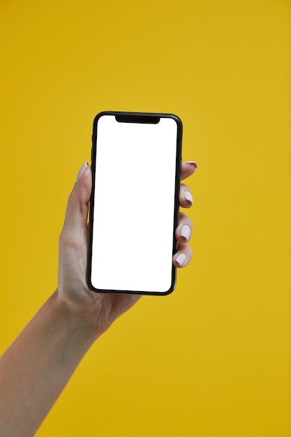 Mano della donna che tiene smartphone mobile con lo schermo bianco su giallo.