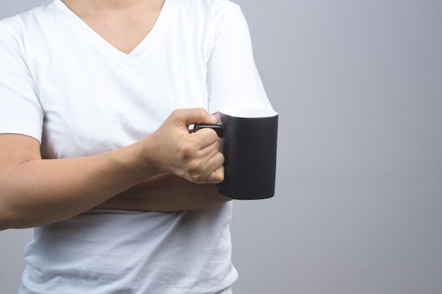 Mano della donna che tiene tazza nera