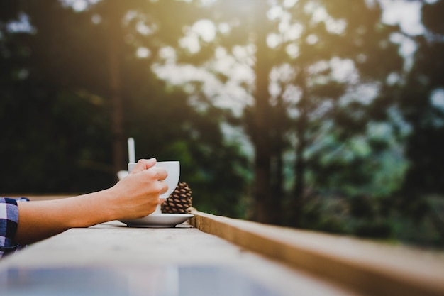 Mano della donna che tiene un bicchiere di caffè nel giardino.