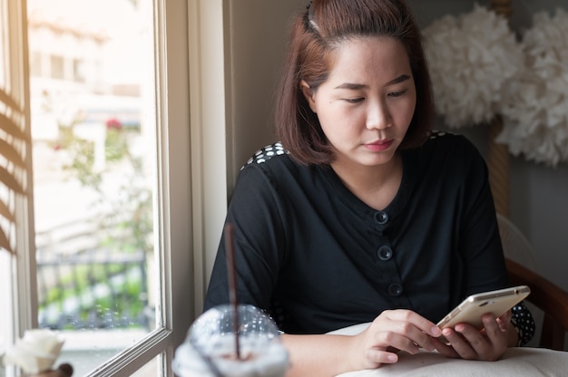 Mano della donna che utilizza telefono cellulare nel caffè