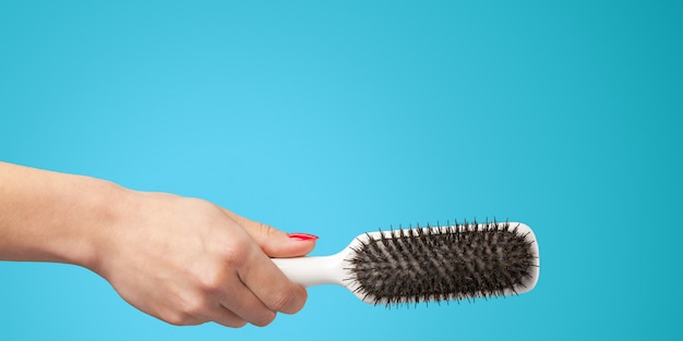 Mano della donna con un pettine isolato su uno sfondo di colore