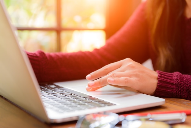 Mano della donna del primo piano che lavora al suo computer portatile.