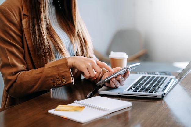 Mano della donna di affari che lavora con il nuovo computer moderno e che scrive sul diagramma di strategia del blocco note come concetto