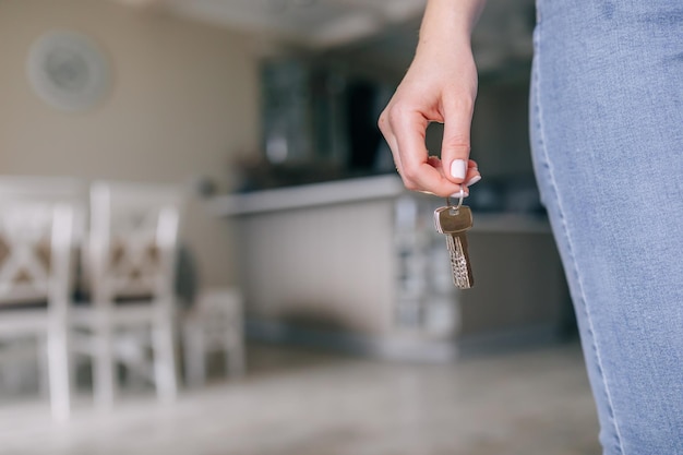 Mano della donna di concetto del bene immobile di affari che tiene le chiavi della casa