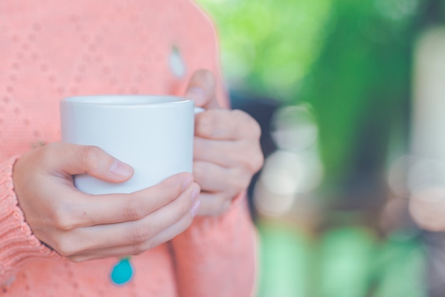 Mano della donna in maglione caldo che tiene una tazza di caffè.