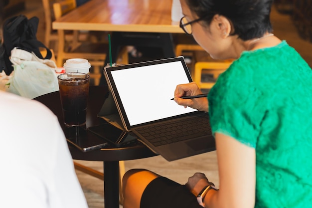 Mano della donna utilizzando la penna stilo sulla tavoletta digitale che lavora nella caffetteria