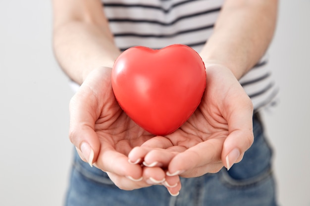 Mano della giovane donna che mostra cuore rosso