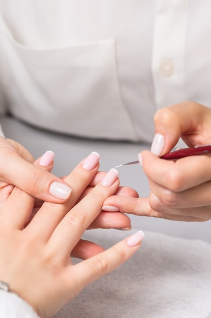 Mano della giovane donna che riceve manicure francese dall'estetista al salone dell'unghia.