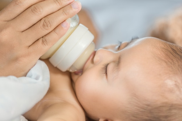 mano della madre che alimenta il latte dalla bottiglia e il bambino che dorme