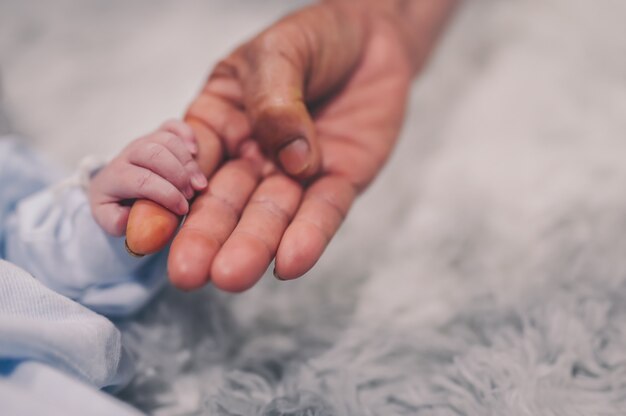 Mano della nonna che tiene il primo piano del dito del nipote del neonato