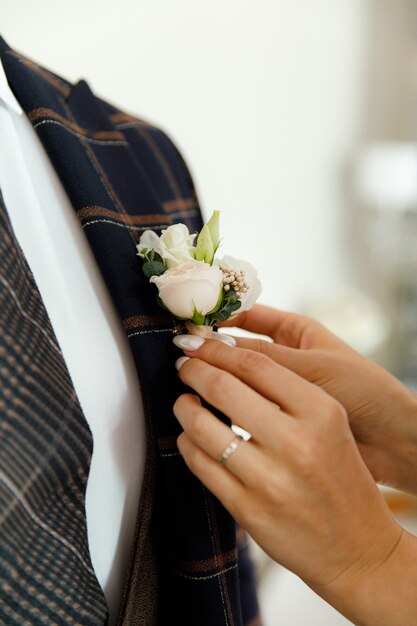 mano della sposa che mette il fiore all'occhiello su uno sposo