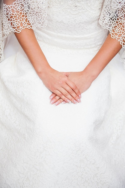 Mano della sposa sul vestito da sposa con una bella manicure