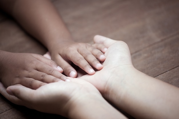 Mano della tenuta della figlia del bambino e della madre insieme ad amore nel tono d&#39;annata di colore