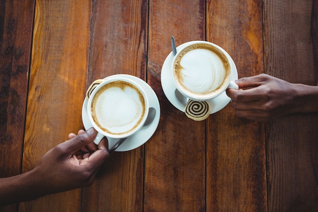 Mano delle coppie che tiene tazza di caffè