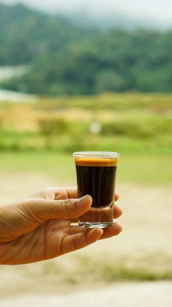 mano delle donne che tiene il vetro del colpo del caffè espresso