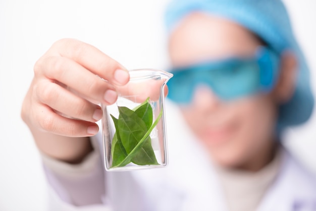 Mano dello scienziato che tiene foglia verde in cuvetta di vetro sul laboratorio. concetto di biotecnologia.