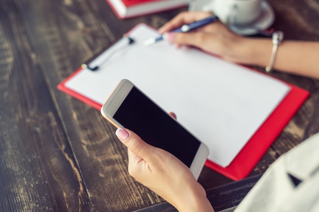 Mano dello smartphone della tenuta della donna