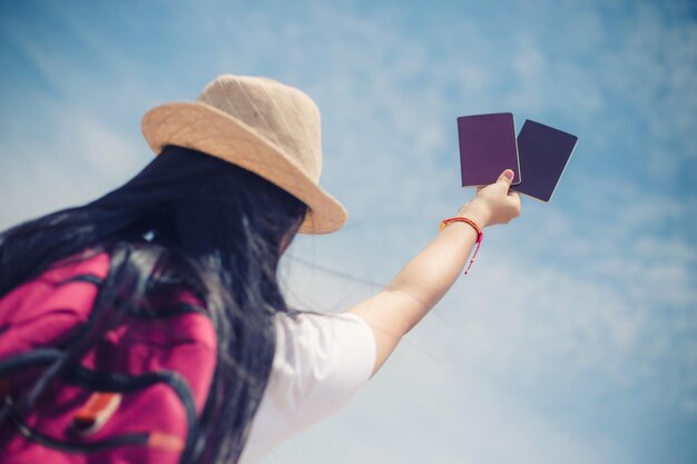 Mano di concetto della gente di viaggio che mostra il passaporto sul cielo