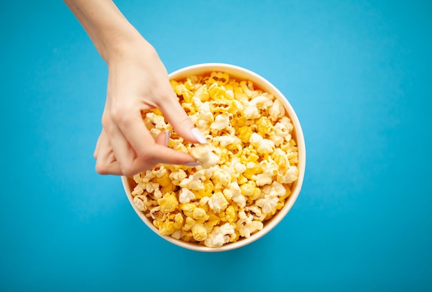 Mano di donna che prende i popcorn dal secchio