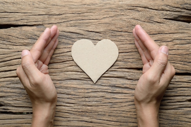 mano di donna con cuore di carta marrone