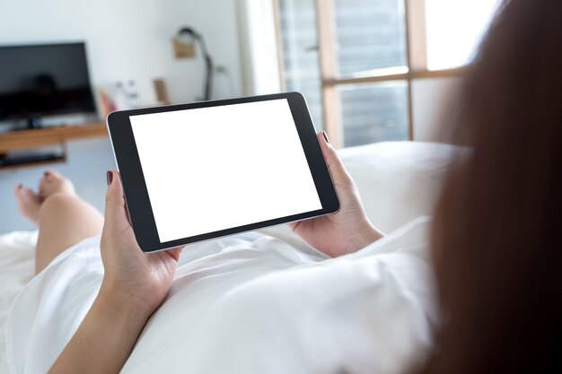 Mano di donna con tablet pc sul letto