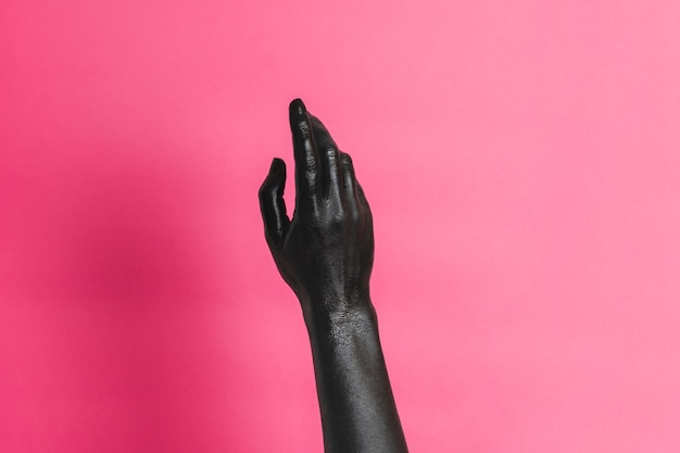 Mano di donna elegante con vernice nera sulla pelle su sfondo rosa concetto artistico di alta moda