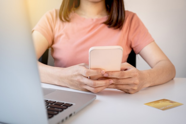 Mano di donna giovane consumatore asiatico utilizzando smartphone e laptop per fare acquisti online