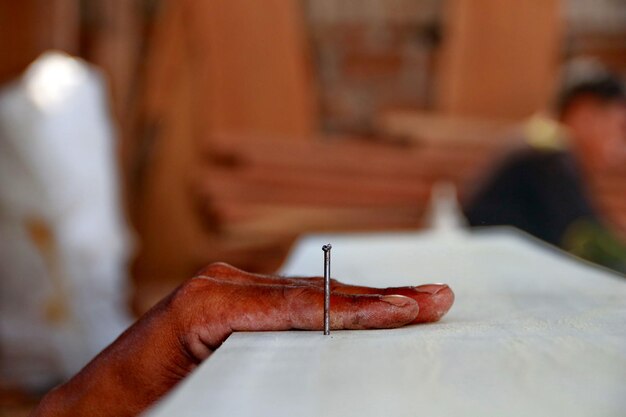 Mano di falegname tagliata con un chiodo sul legno