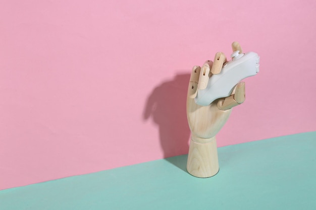Mano di legno che tiene il controller moderno su sfondo blu pastello rosa Ombra alla moda Concept art Minimalismo Layout creativo