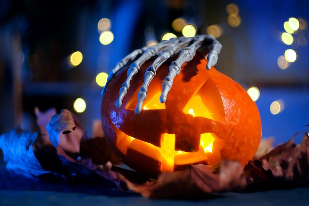 Mano di scheletro con testa di zucca di Halloween