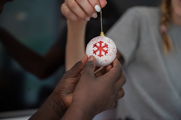 Mano di un bambino che tiene in mano una pallina di natale bianca e rossa per le vacanze