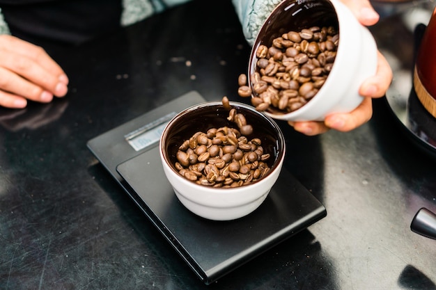 Mano di un dipendente irriconoscibile che pesa i chicchi di caffè.