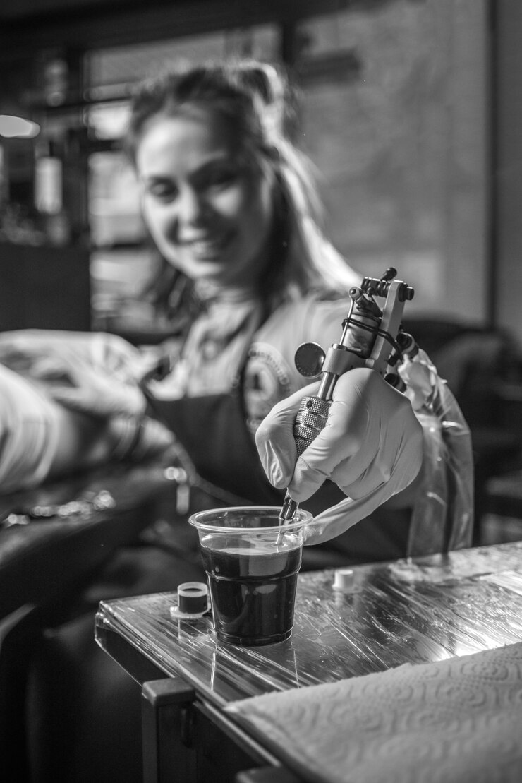 Mano di un tatuatore professionista e una pistola per tatuaggi.