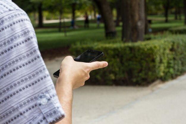 Mano di un uomo anonimo che parla sul telefono nel parco.