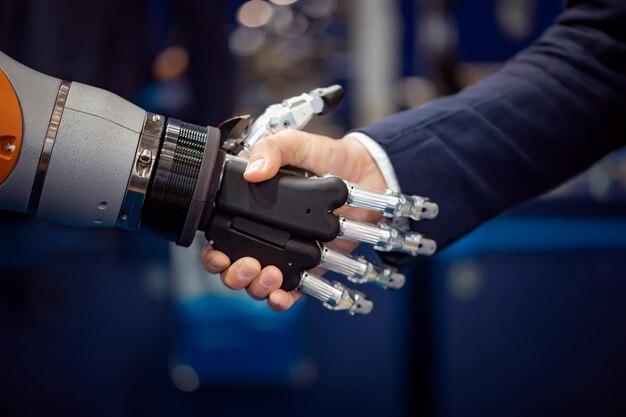 Mano di un uomo d'affari che stringe la mano a un robot Android. Il concetto di interazione umana con l'intelligenza artificiale.