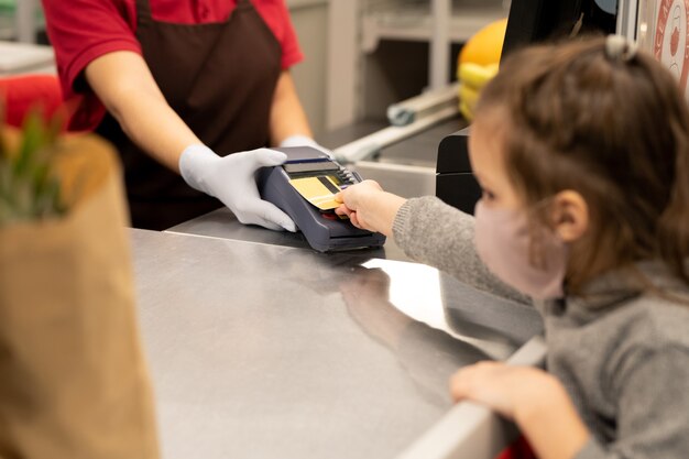 Mano di un uomo maturo contemporaneo con smartwatch che tiene il polso sulla macchina di pagamento mentre è in piedi accanto al registratore di cassa nel supermercato