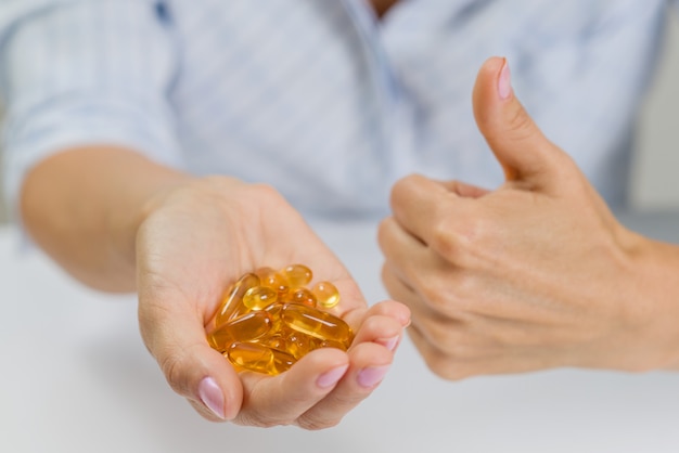 Mano di una donna con olio di pesce Omega-3 capsule