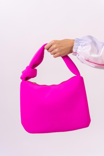 Mano di una donna con una borsa rosa su uno studio di moda sfondo bianco