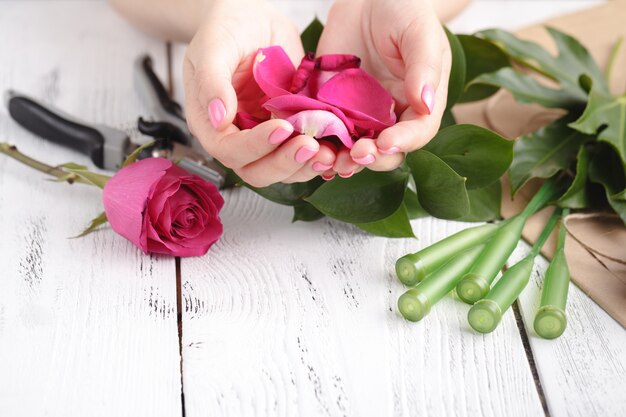 Mano di una donna fiorista piena di petali di rose per il matrimonio