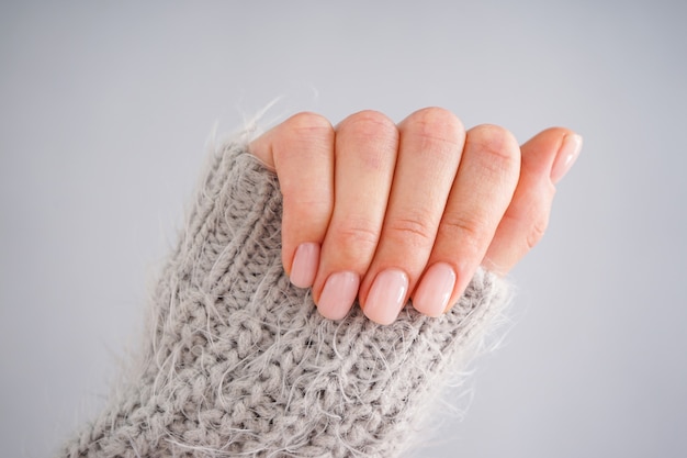 Mano di una giovane donna con bella manicure su uno sfondo grigio. Manicure femminile. Lay piatto, primo piano.