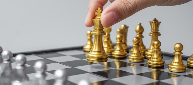 Mano di uomo d'affari in movimento figura di re degli scacchi d'oro durante la competizione di scacchiera.